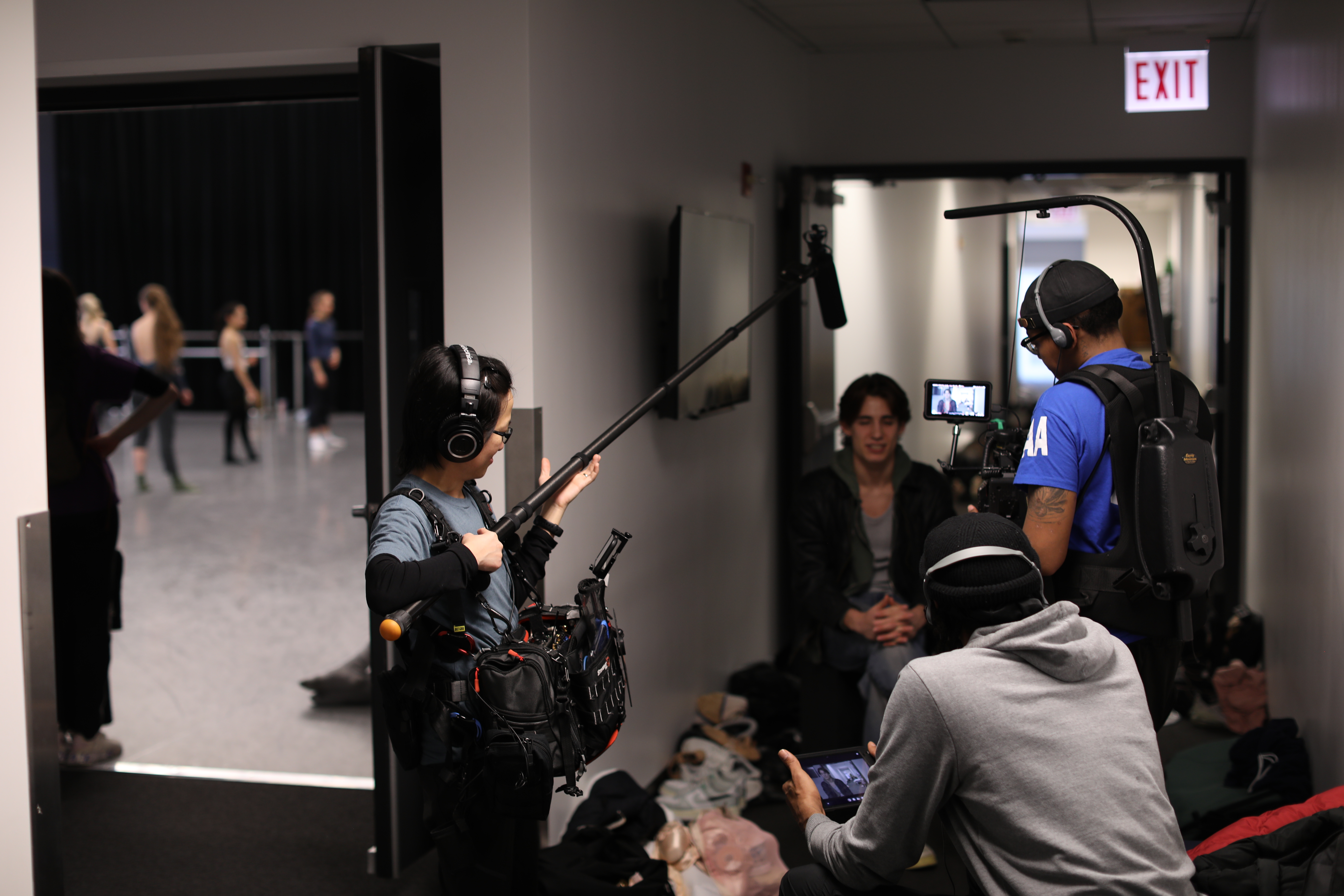 Shuling Yong carrying a sound mixer and boom pole for a sit-down interview with a ballet dancer at the Joffrey Ballet, alongside Director Cam Be and Cinematographer C'airra Cortez